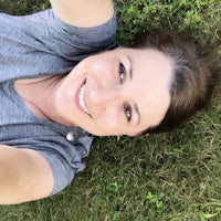 a woman laying on the grass taking a selfie